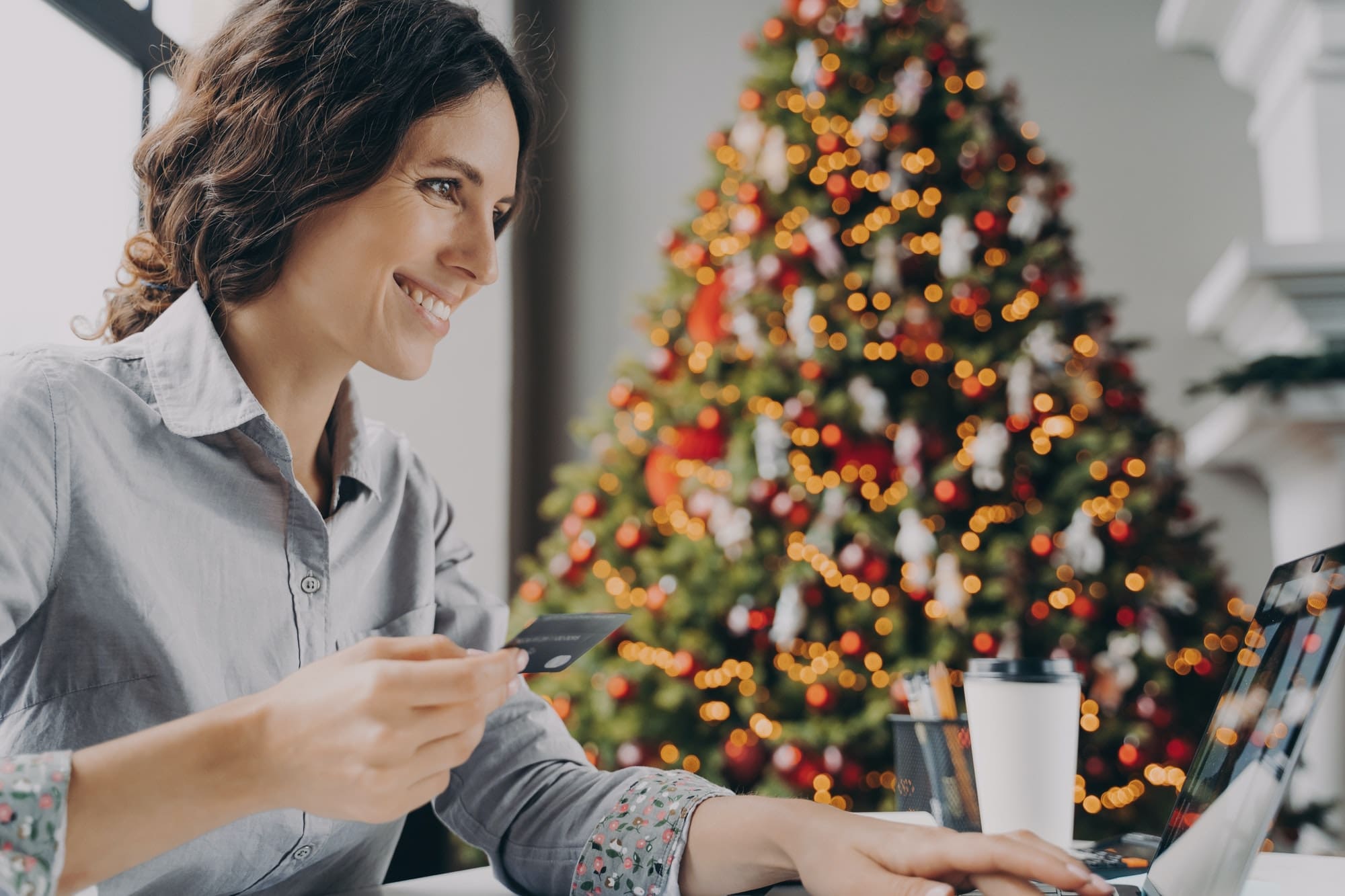 Happy young woman doing online shopping on laptop computer at home during Winter holidays sales
