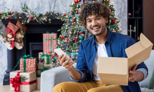 Portrait of a happy buyer in online store, a man smiles and looks at the camera, holds a phone and