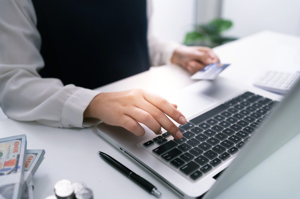 Woman holding credit card and using laptop computer for Internet online e-commerce shopping